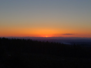 The gates of dawn glow orange and gold out beyond the mountains at the edge of the black horizon